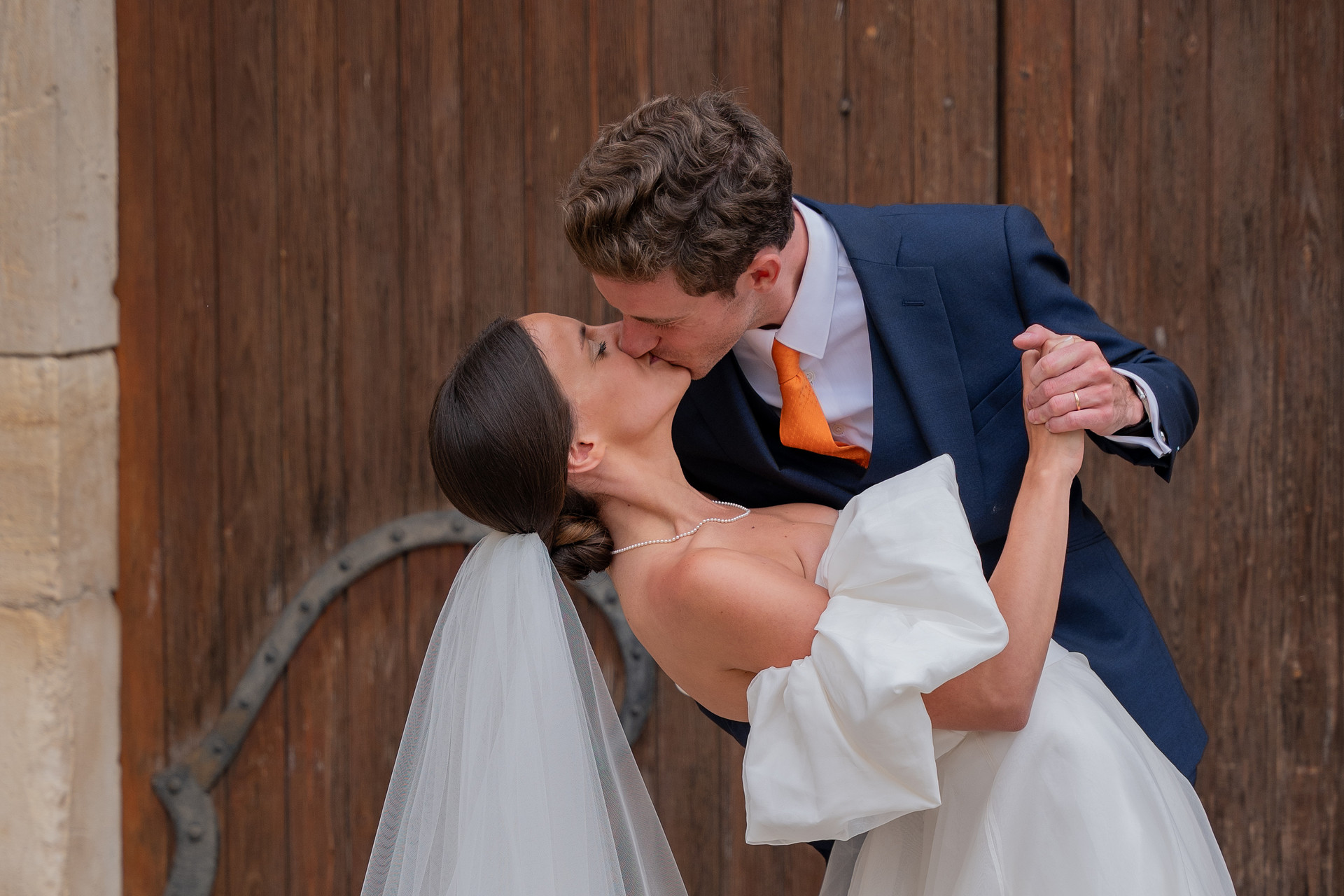 Rêveuse d'étincelles - Tatiana MAURINES - Photographe et biographe sur Écully, Lyon et la région Rhône-Alpes. Photographe à écully, image d'un couple de mariés s'embrassant devant une porte en bois.