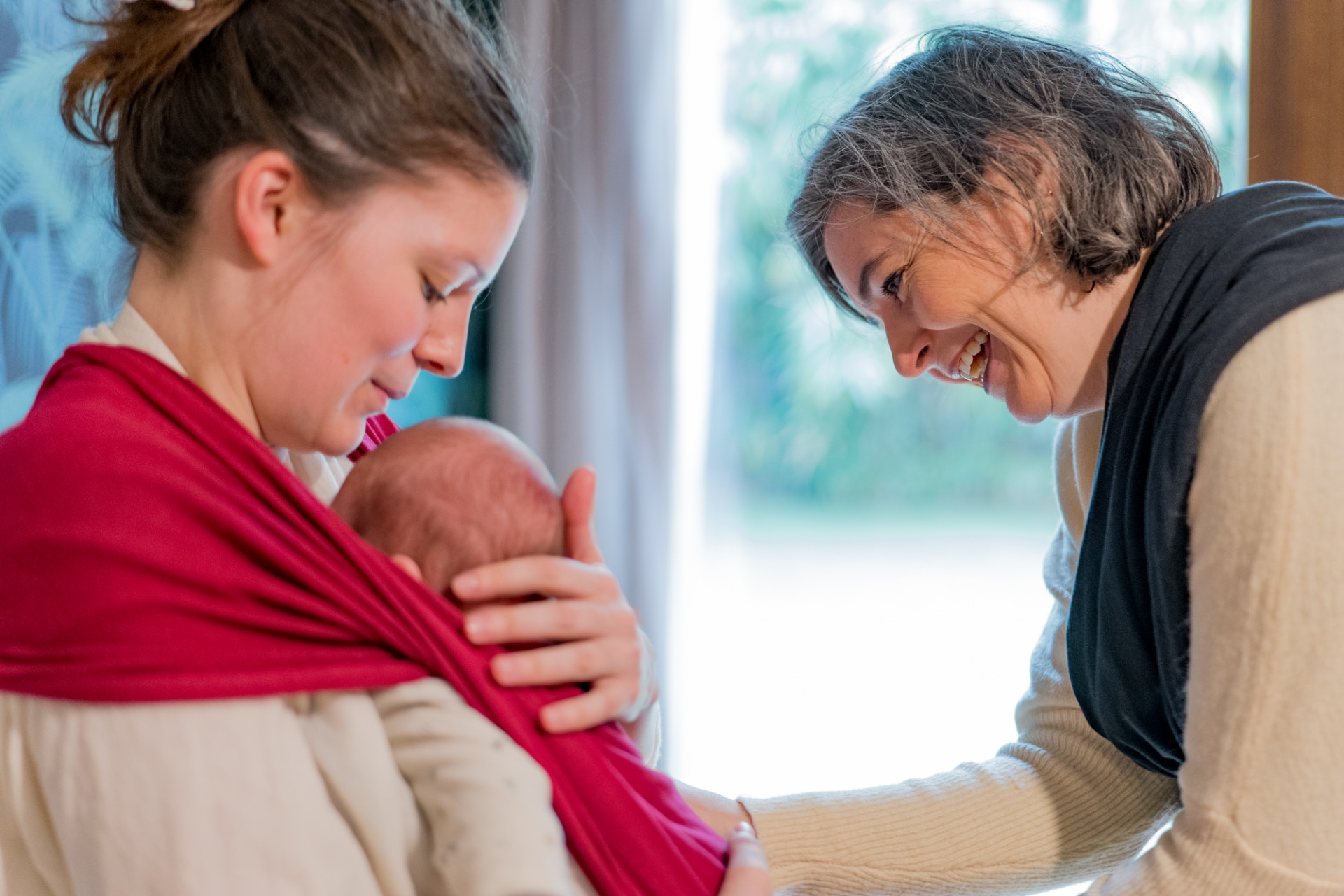 Rêveuse d'étincelles - Tatiana MAURINES - Photographe et biographe sur Écully, Lyon et la région Rhône-Alpes. Photographe à écully, cette image illustre une séance photo reportage métier. Une conseillère en portage installe le bébé d'une cliente.