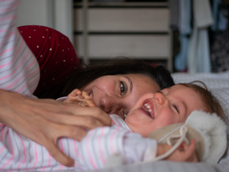 Rêveuse d'étincelles - Tatiana MAURINES - Photographe et rédactrice sur Écully, Lyon et la région Rhône-Alpes. Séance photo de famille à Lyon. Une maman fait des chatouille à sa fille sur le lit.