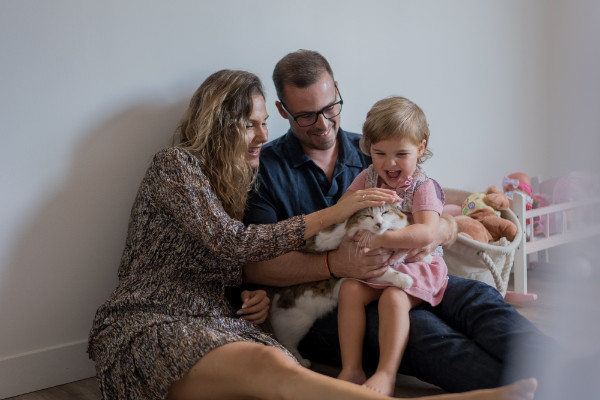 Rêveuse d'étincelles - Tatiana MAURINES - Photographe et biographe sur Écully, Lyon et la région Rhône-Alpes. Photographe à écully. Extrait d'une séance famille à domicile. Une petite fille rit avec son chat sous les yeux de ses parents.